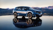 Blue BMW iX3 electric SUV parked on a reflective surface with mountains and sky in the background