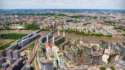 CGI rendering of Battersea Power Stations future development with new buildings and green spaces along the River Thames.