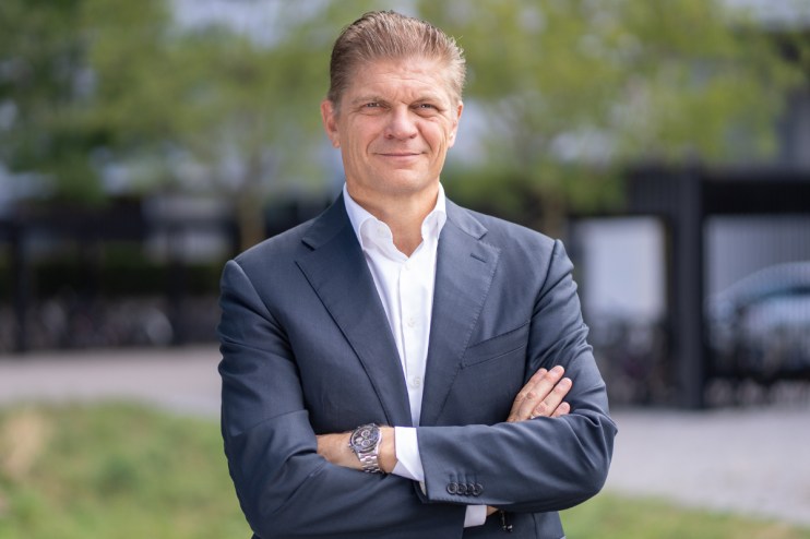 Bjorn Sibbern, Six Exchange executive, in a dark suit with arms crossed, smiling outdoors.