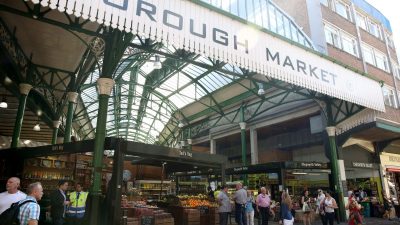 Borough Market entrance with vendors, fresh produce, and shoppers under the iconic green roof structure