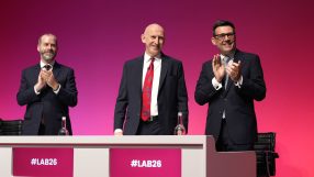 Andy Burnham, Peter Kyle, and Jonathan Reynolds applauding at a #LAB26 event with a pink background.