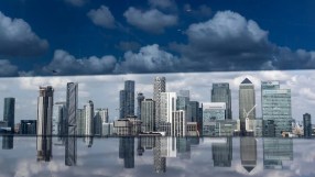 London financial district skyscrapers reflecting in water, under a dramatic cloudy sky