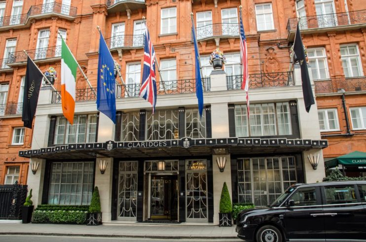 Claridges Hotel exterior with international flags, including the Union Jack, and a black taxi outside