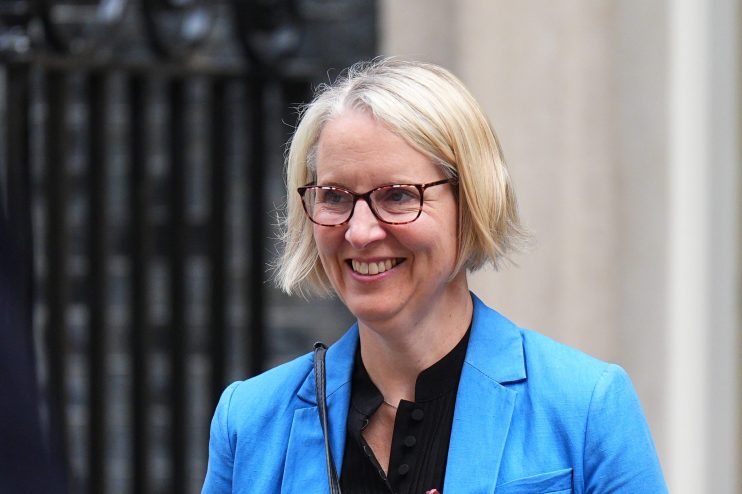 Emma Reynolds, a blonde woman in glasses and blue blazer, smiling outdoors