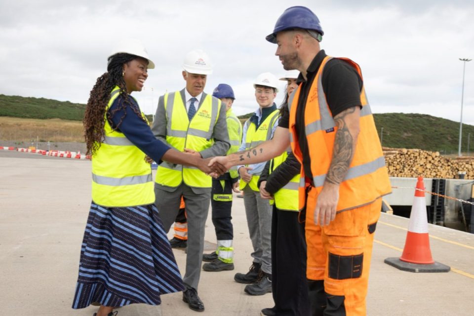 Fahnbulleh shaking hands with a man in a hard hat and high-vis vest at North Sea port.