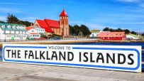 Welcome to the Falkland Islands sign with Stanley harbor and Christ Church Cathedral in background.