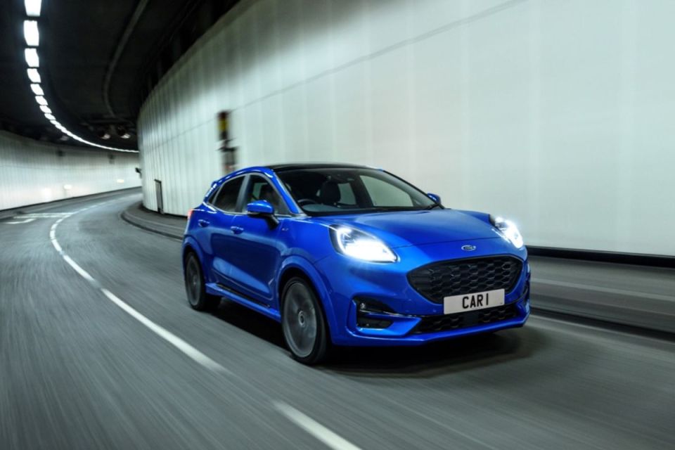 Blue Ford Puma SUV driving through a tunnel with headlights on.