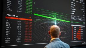 Man views London Stock Exchange screen displaying stock prices, Fallers list, and financial data.