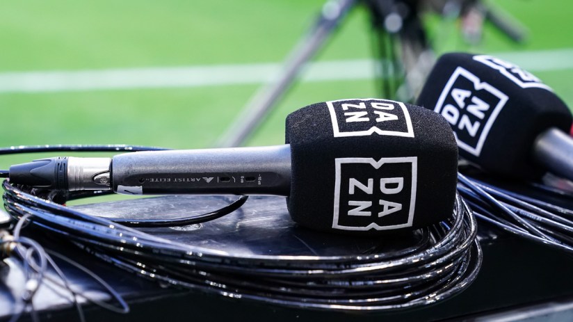 DAZN branded microphones and cables on a surface with a green field in the background