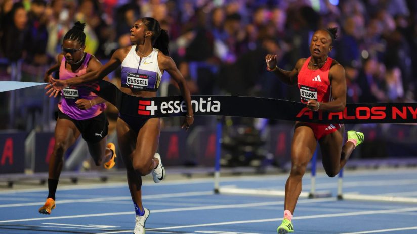 Three female athletes, Charlton, Russell, and Stark, crossing the finish line in a close race, action shot
