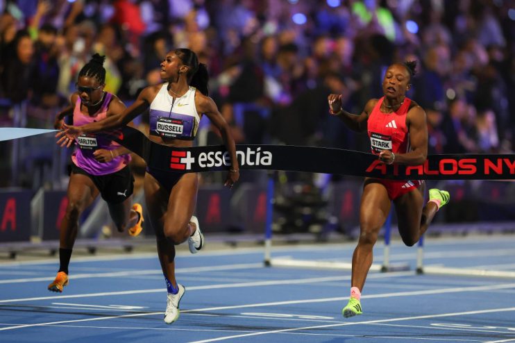 Three female athletes, Charlton, Russell, and Stark, crossing the finish line in a close race, action shot