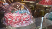 Bulk display of pink and white gummy candies in a clear dome on a wooden barrel in a candy store