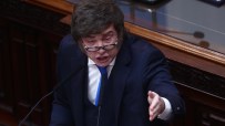 Javier Milei speaking passionately at a podium, gesturing with his right hand, in a formal setting.