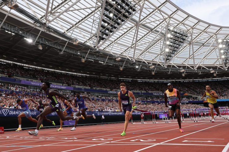 Athletes sprint on a track during a hurdles race at the London Diamond League athletics meet.