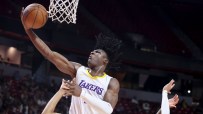 Lakers basketball player in white jersey performs a layup, ball near the net, during a game