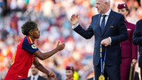 FIFA President Gianni Infantino with a gold medal, interacting with a young footballer in a red jersey.