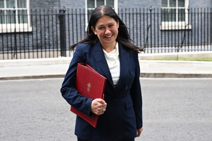 Michelle Donelan, Secretary of State, smiling and holding a red folder outside a building