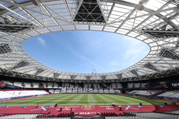 Wide view of an empty London Stadium, home of West Ham United, with a bright blue sky visible through its open roof.