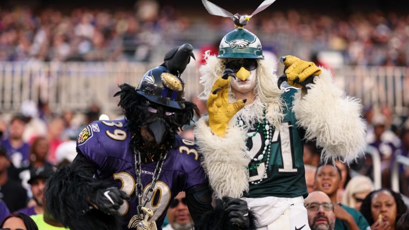 Two football fans in elaborate bird costumes, one as a Baltimore Raven, the other a Philadelphia Eagle