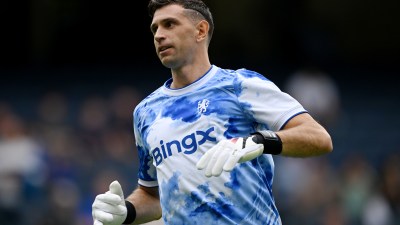 Emiliano Mart&iacute;nez in a blue and white tie-dye Aston Villa goalkeeper kit with BingX sponsor logo and white gloves.