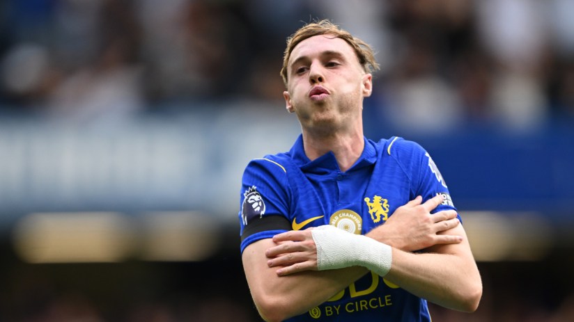 Footballer in blue jersey with bandaged arm, celebrating on field.