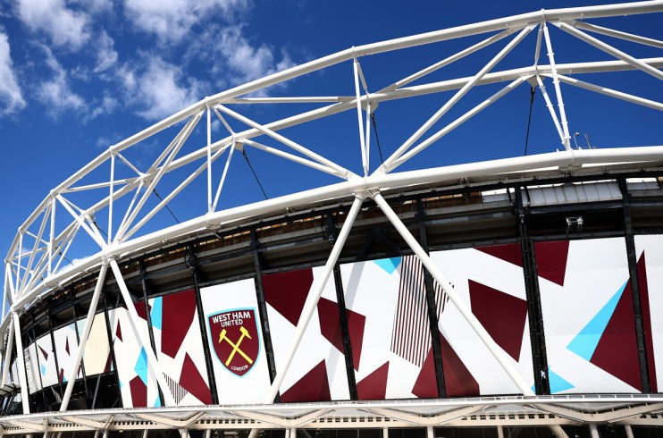 Exterior of London Stadium (formerly Olympic Stadium) with West Ham United logo against a blue sky
