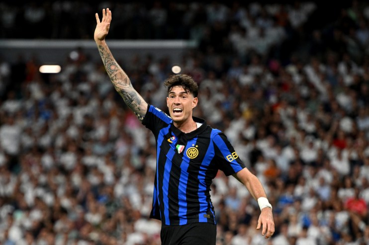Footballer in a black and blue striped jersey with his arm raised on a crowded field