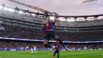 FC Barcelona player Raphinha celebrates a goal in a packed stadium during a UEFA Champions League match.