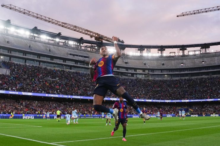FC Barcelona player Raphinha celebrates a goal in a packed stadium during a UEFA Champions League match.