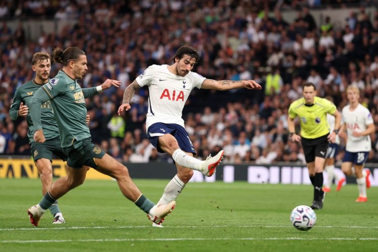 Tottenham player kicking a soccer ball during a match, opponent defender near, referee in background