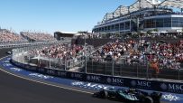 Formula 1 race car on track with fans in grandstands and luxury boxes under a sunny sky