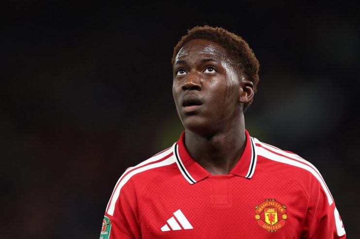 Young male football player in a red Manchester United jersey, looking up with sweat on his face.