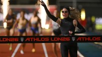 Runner in black athletic wear celebrating victory at finish line, making a peace sign after winning race.