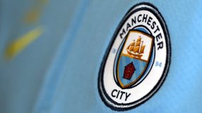 Close-up of the Manchester City football club crest on a light blue jersey.
