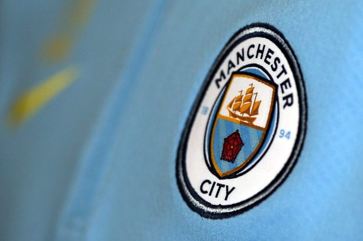 Close-up of the Manchester City football club crest on a light blue jersey.