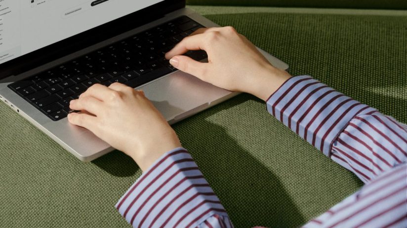 Hands typing on a laptop keyboard, screen showing business data or software interface.