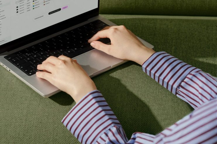 Hands typing on a laptop keyboard, screen showing business data or software interface.