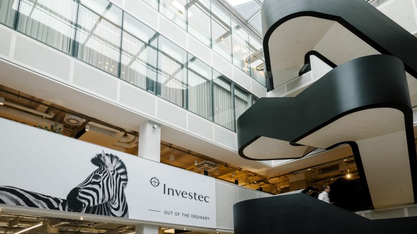 Modern Investec office interior with zebra branding, glass walls, and a winding black staircase.