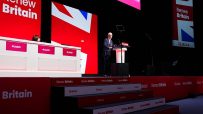 Keir Starmer speaking at a Labour Party conference with Renew Britain banners and Union Jack design