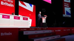 Keir Starmer speaking at a Labour Party conference with Renew Britain banners and Union Jack design