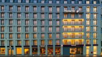 Premier Inn hotel building in Leipzig, Germany, at dusk with illuminated windows and ground floor businesses