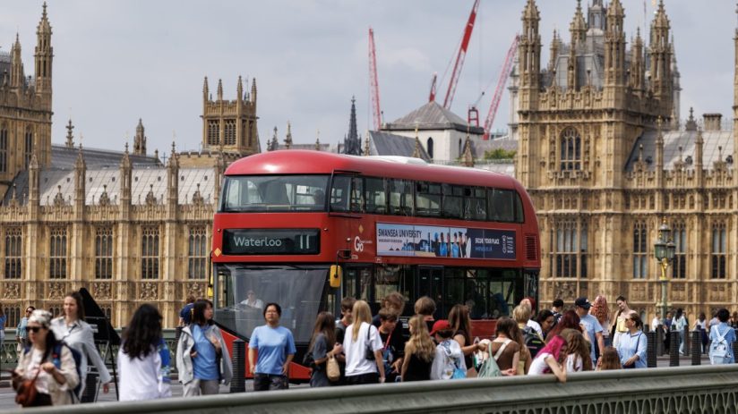 London red double-decker bus with Waterloo destination sign, driving past the Houses of Parliament.