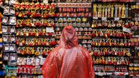 Person in red poncho browsing a stall filled with London tourist keyrings and souvenirs like magnets and teddy bears.