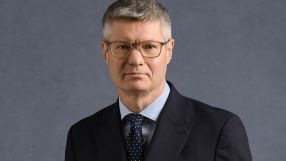 Lord Wolfson, CEO of Next Plc, wearing a dark suit, light blue shirt, and spotted tie