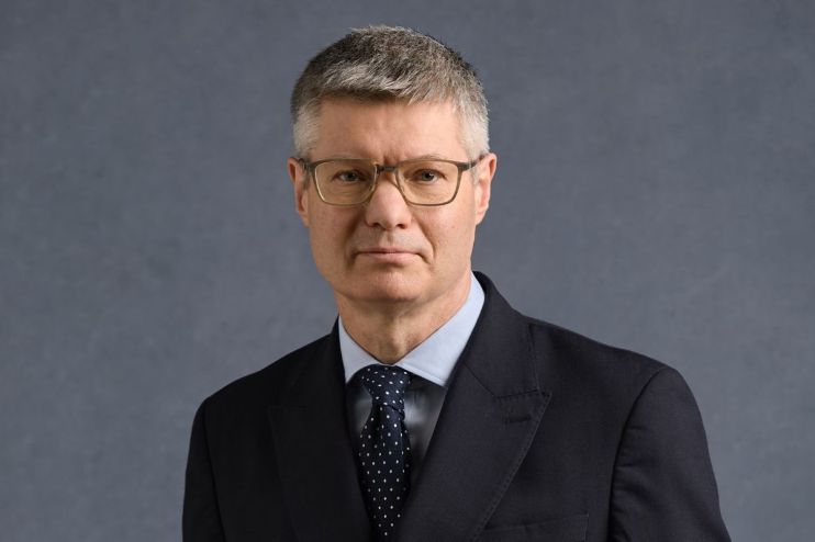 Lord Wolfson, CEO of Next Plc, wearing a dark suit, light blue shirt, and spotted tie
