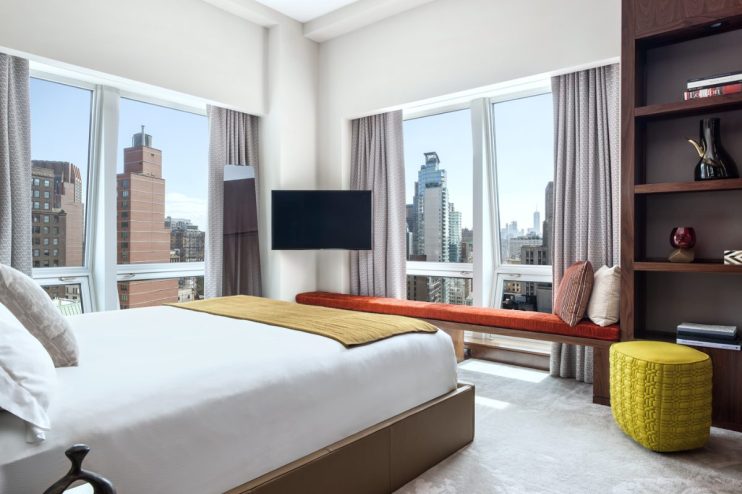 Luxurious bedroom at The Langham New York hotel with city views, modern furniture, and large windows