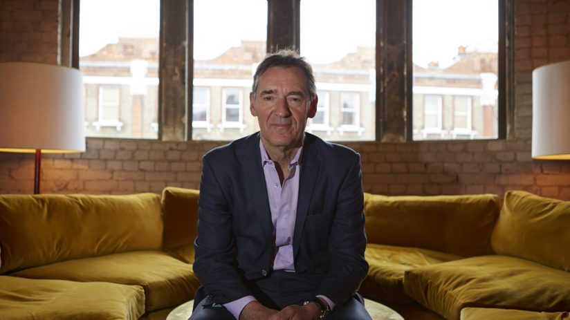 Jim ONeill, economist and former Goldman Sachs chief, seated on a yellow sofa in a brick-walled room