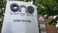 One Savings Bank (OSB) House sign in front of a brick building and green trees.