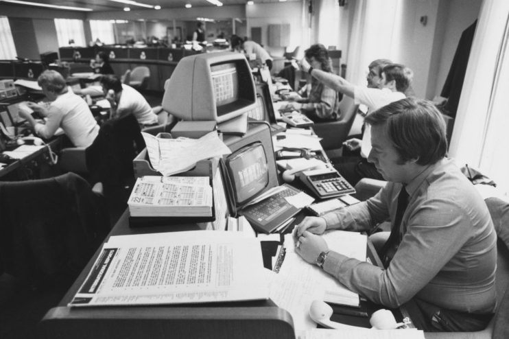 Office worker in the 1990s, surrounded by vintage computer monitors, calculators, and paper documents.