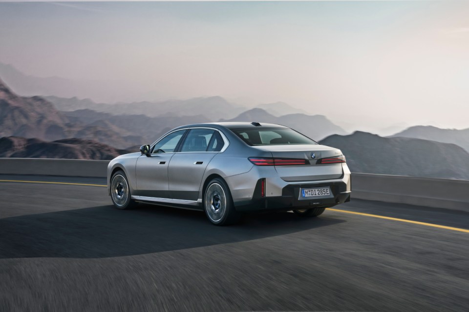 Silver BMW 7 Series driving on a winding road with mountains in the background